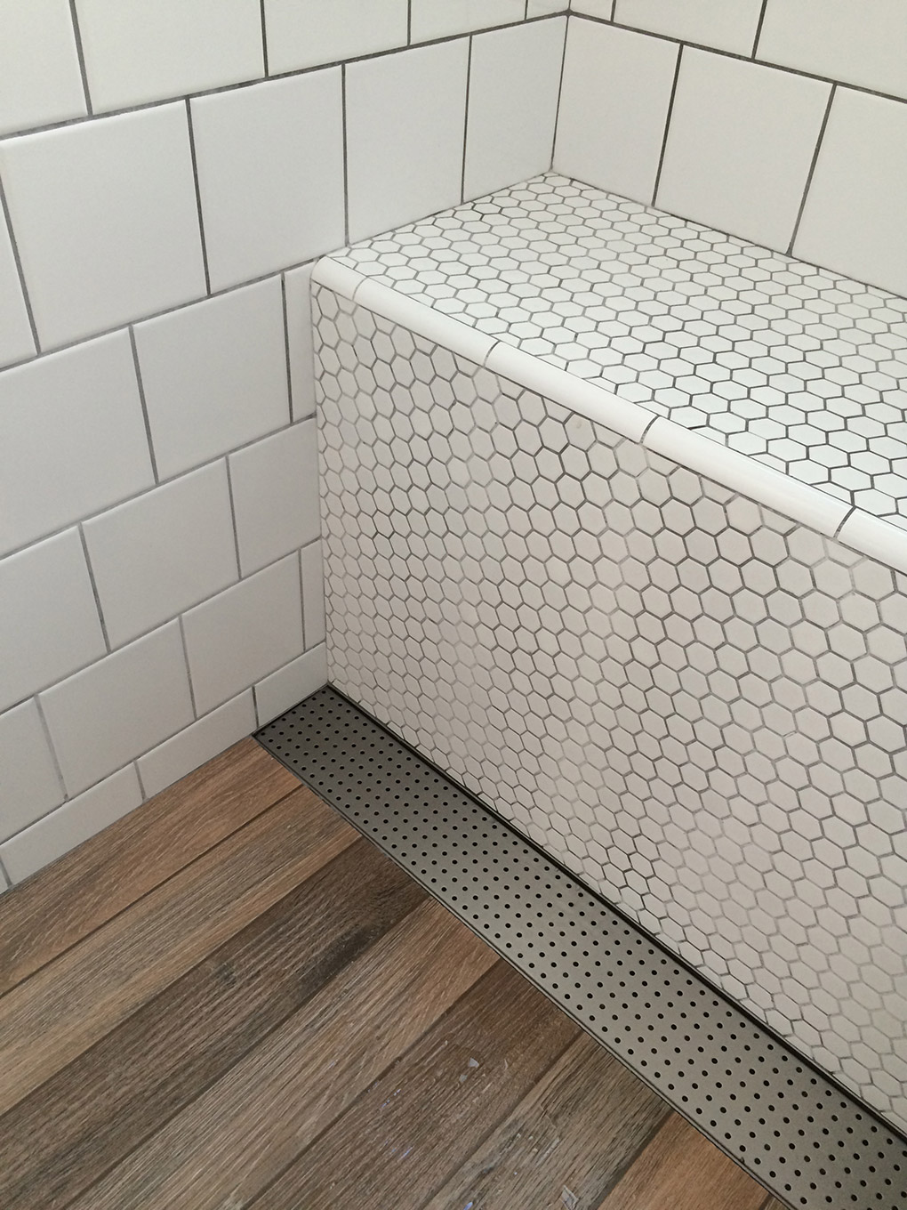 ralo linear inox no piso de madeira do banheiro retro com azulejo branco