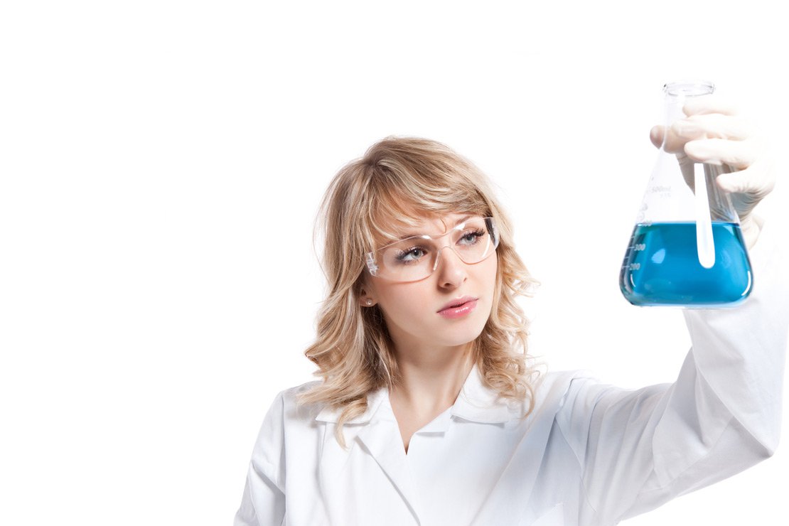 Cientista mulher olhando uma experiencia azul de jaleco branco e oculos de segurança